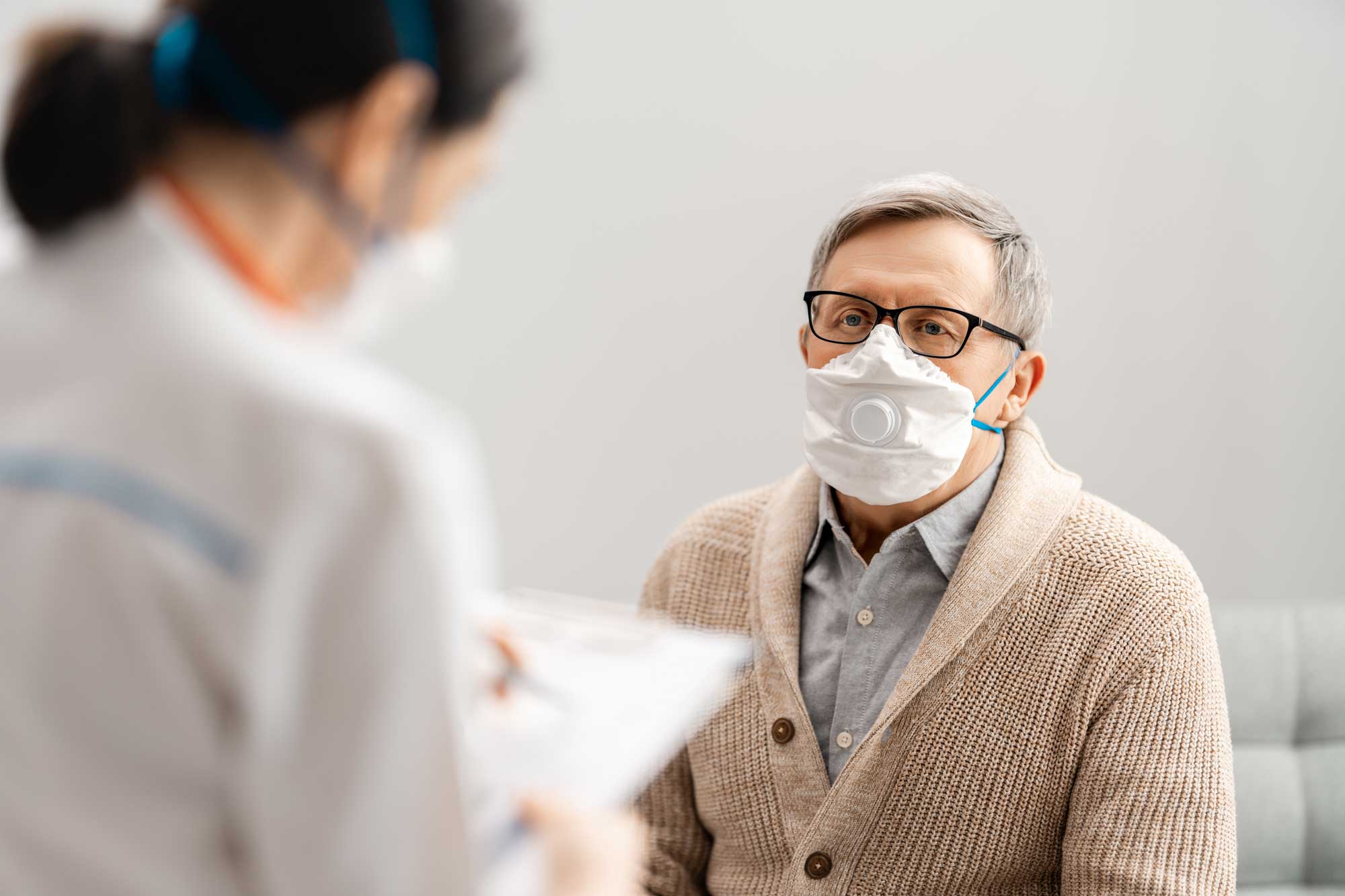 Corona: Patient mit Maske beim Arzt