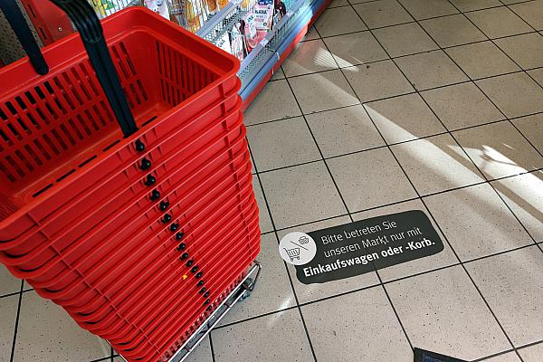 Einkaufskörbe mit Corona-Hinweis in Supermarkt, über dts Nachrichtenagentur