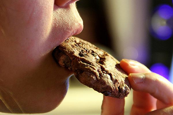 Junges Mädchen isst einen Schokoladenkeks, über dts Nachrichtenagentur