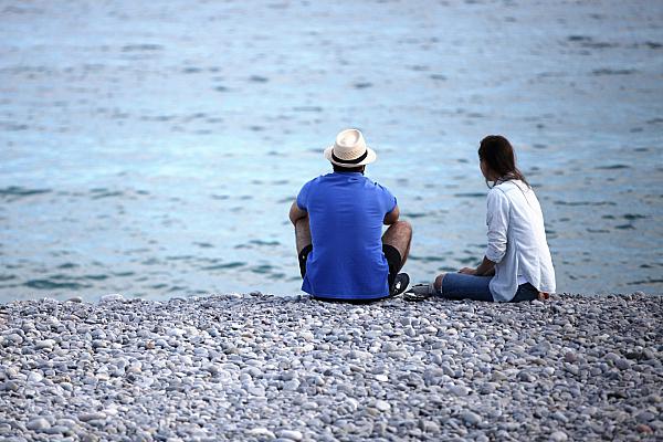 Mann und Frau sitzen am Strand, über dts Nachrichtenagentur