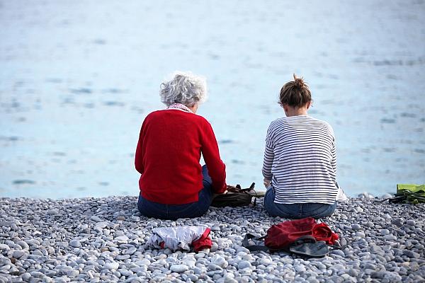 Alte und junge Frau sitzen am Strand, via dts Nachrichtenagentur